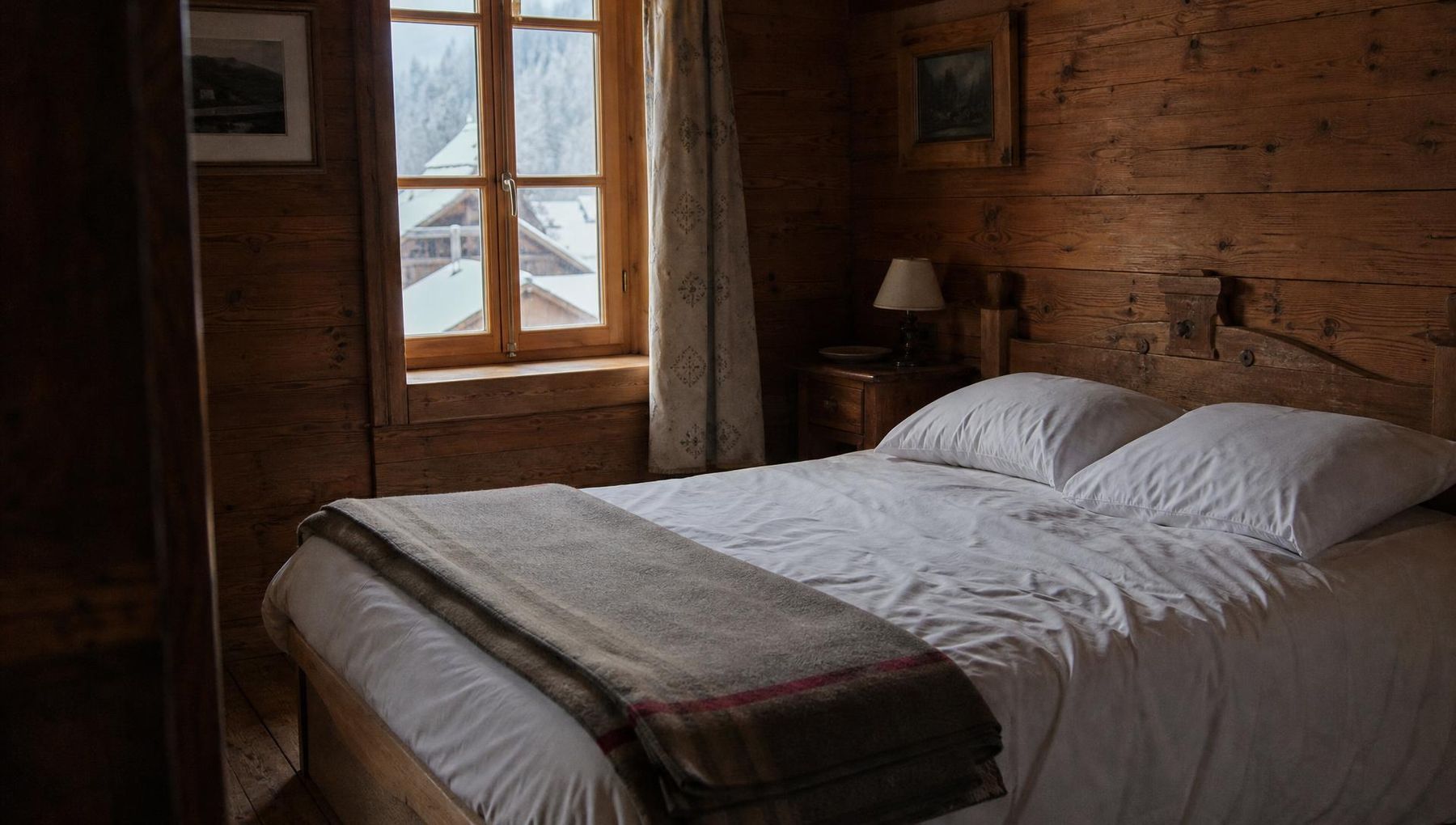 Lit fait avec du linge de coton blanc dans une chambre de chalet alpin